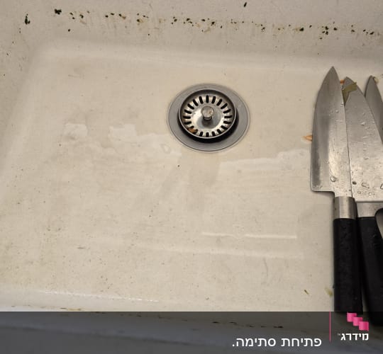 כיור עם ניקוז וסכינים מונחים בצד